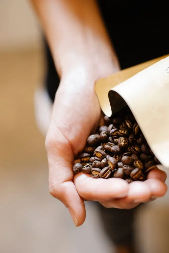 Man pouring coffee beans into his hands.